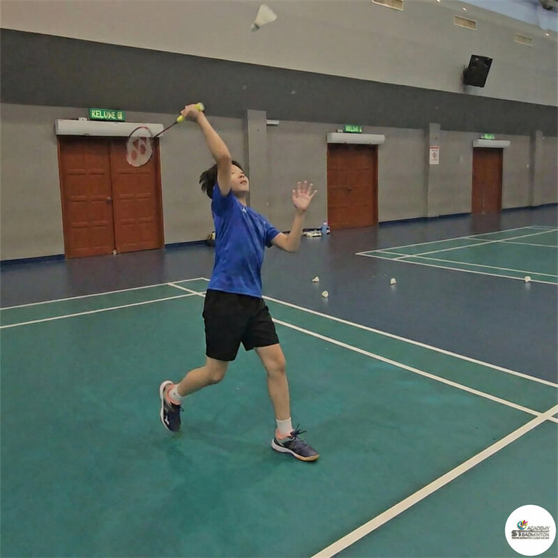 Coach correcting racket grip for a junior student during PBF Level 1 badminton foundation class