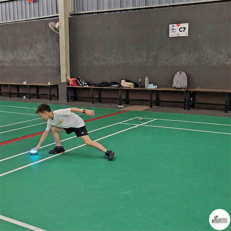 Young student practicing foundation footwork patterns for PBF Level 1 assessment at ST Badminton Academy